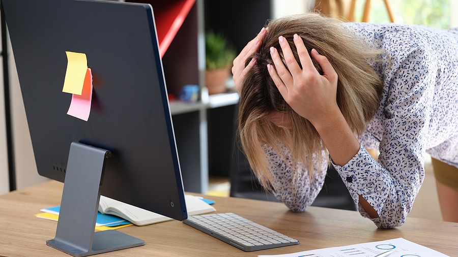 woman with her hands and her head in front of computer monitor
