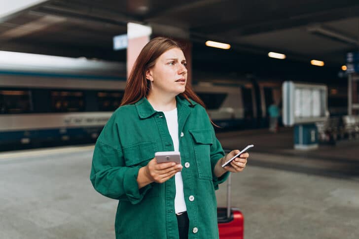 Woman standing on train platform looking confused