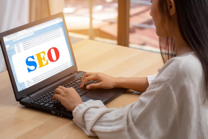Woman at a keyboard at a page with SEO written on it