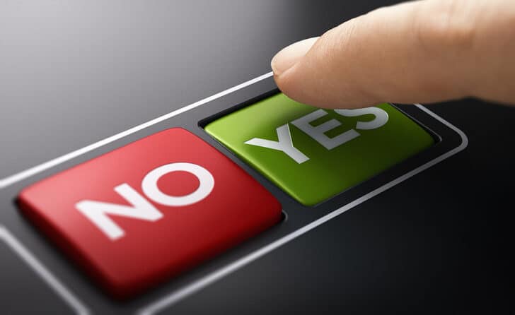 Person pressing a green "YES" button that is next to a "NO" button